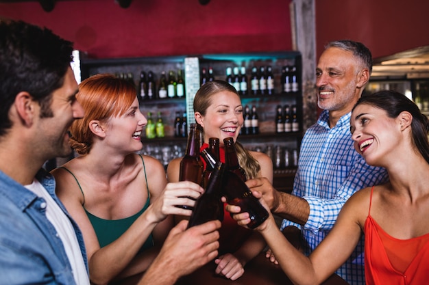 Amici che tostano la bottiglia di birra in discoteca