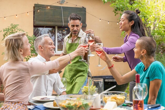 Friends toasting with big smile around the table at house patio diner