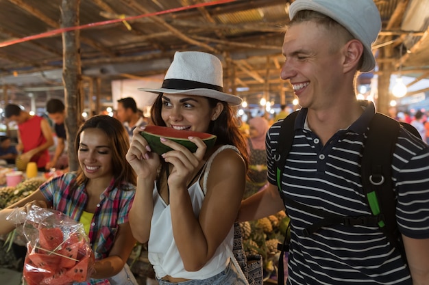 Amici turisti degustazione di anguria sul tradizionale mercato di strada in asia