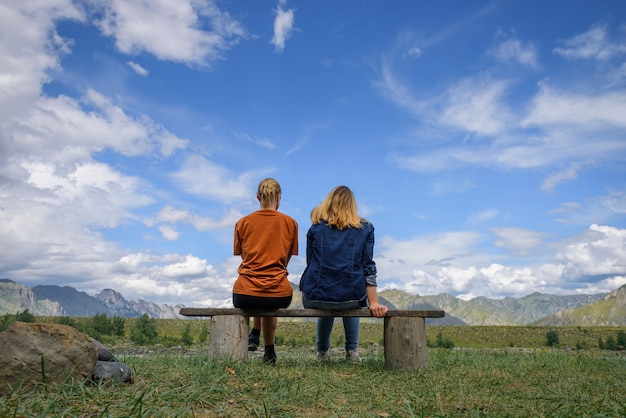 友達が旅行し、晴れた日に青い空の下で山脈の壮大な景色を眺める