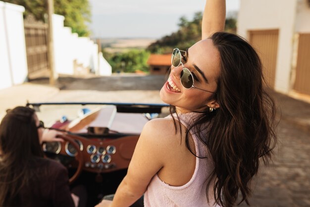 Friends traveling together in an old convertible car. Summer enjoyment concept