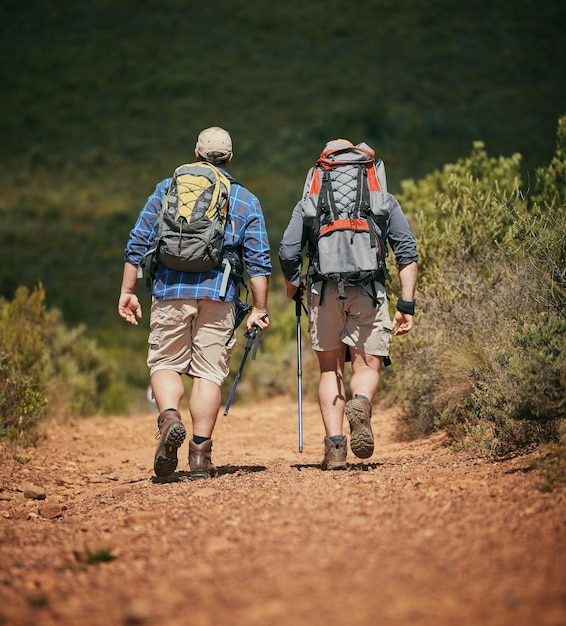 Friends trekking nature while hiking in a forest together being\
active and bonding outdoors active male travel on a path in the\
woods enjoying a physical challenge while on trekking\
adventure