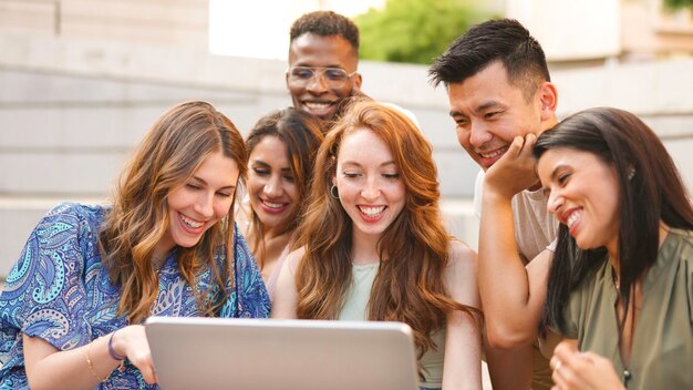 Friends using a laptop in the street