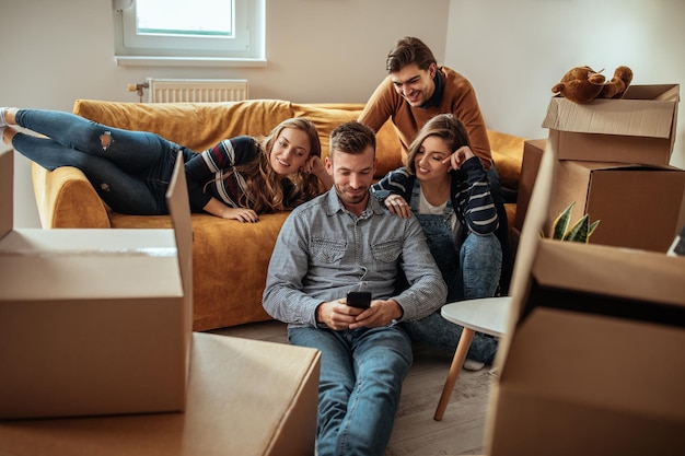 Friends using a technology while relaxing during moving into new home