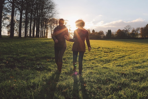 Photo friends walking on grassy field at park