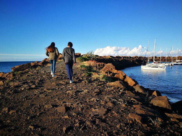 Foto amici che camminano sulla roccia sul mare contro il cielo