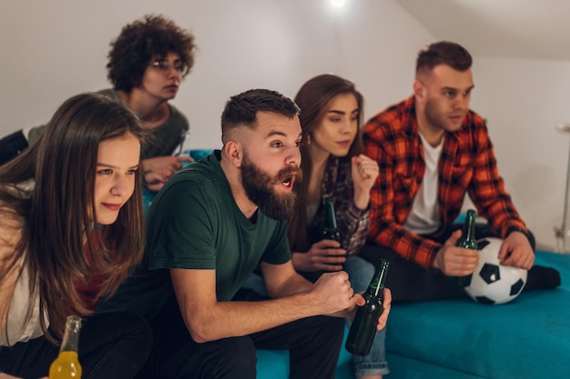 Friends watching football game at home and cheering