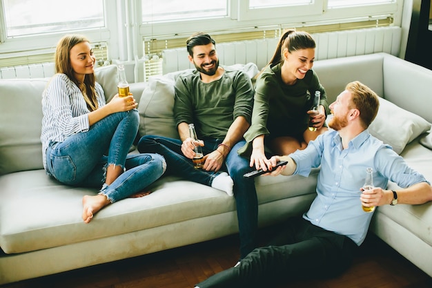 Friends watching TV , drinking cider and having fun in the room