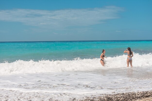 写真 ビキニを着た友達が空に向かって海に立っています