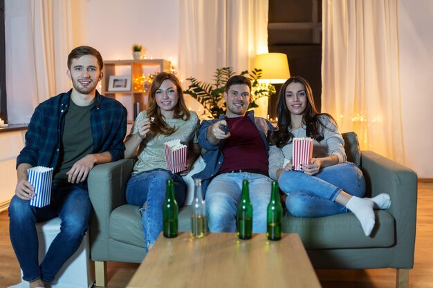 friends with beer and popcorn watching tv at home