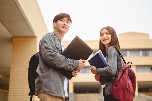 写真 大学のキャンパスに立って本と話す友人たち