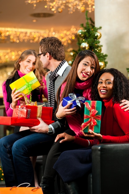 Friends with Christmas presents and bags in mall