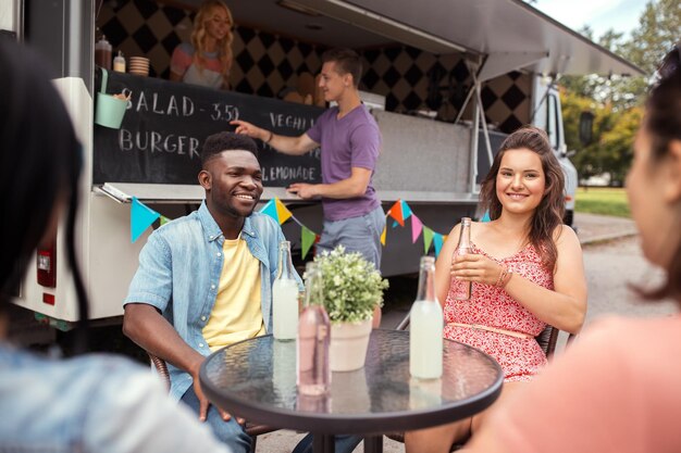 friends with drinks sitting at table at food truck