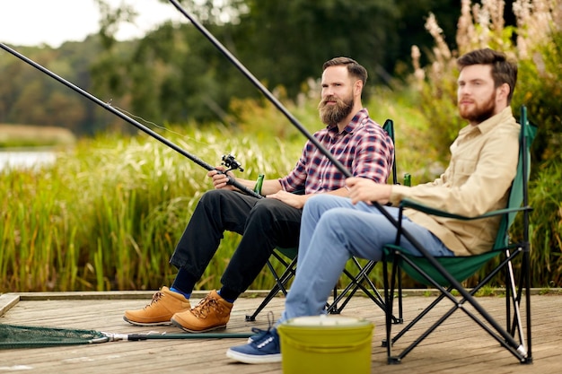 friends with fishing rods at lake or river