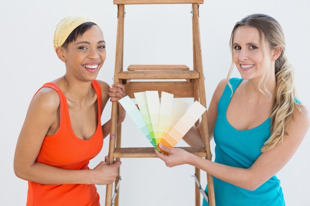 Friends with ladder choosing color for painting a room