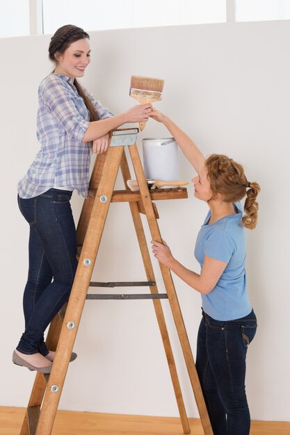 Friends with paintbrush and can on ladder in a new house