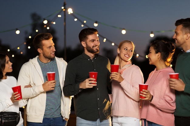 friends with party cups on rooftop at night