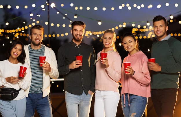 friends with party cups on rooftop at night