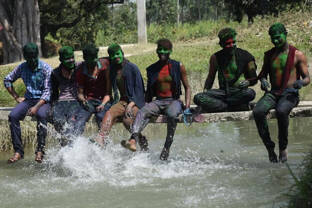 Foto amici con la vernice in polvere seduti sul ponte pedonale sul lago