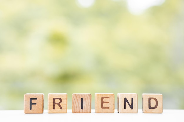 Friends word is written on wooden cubes on a green summer background Closeup of wooden elements