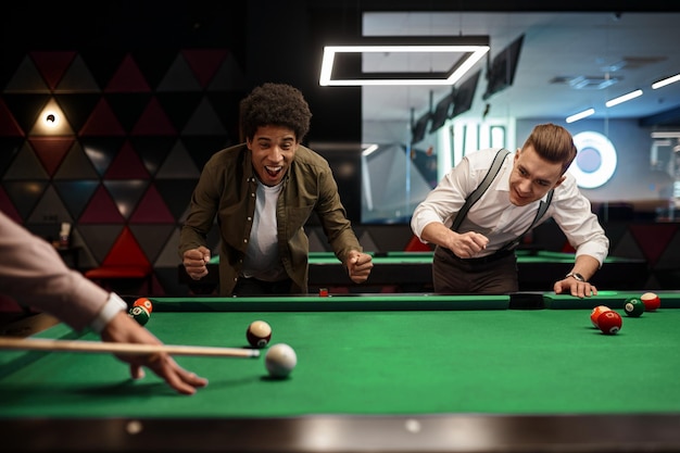 Friends young people group playing billiards together, nightlife club recreation enjoyment