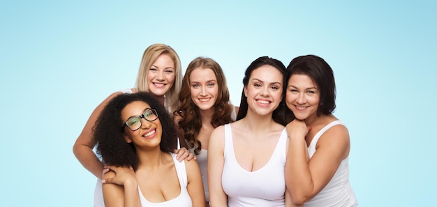 Photo friendship, beauty, body positive and people concept - group of different happy women in white underwear over blue background
