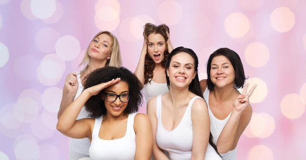 Friendship, beauty, body positive and people concept - group of happy plus size women in white underwear having fun and making faces over rose quartz and serenity lights background