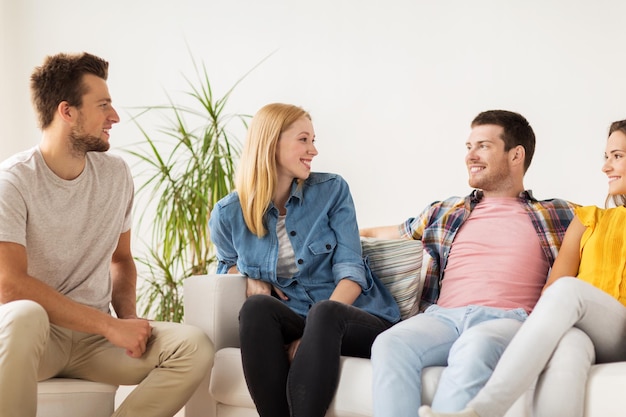 friendship, communication and people concept - group of happy friends talking at home