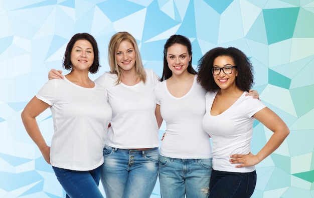 友情、多様性、ボディ ポジティブ、人々 のコンセプト - 青い低ポリ背景に抱きしめる白い t シャツを着た幸せな異なるサイズの女性のグループ
