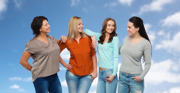 friendship, fashion, body positive, diverse and people concept - group of happy different size women in casual clothes over blue sky and clouds background