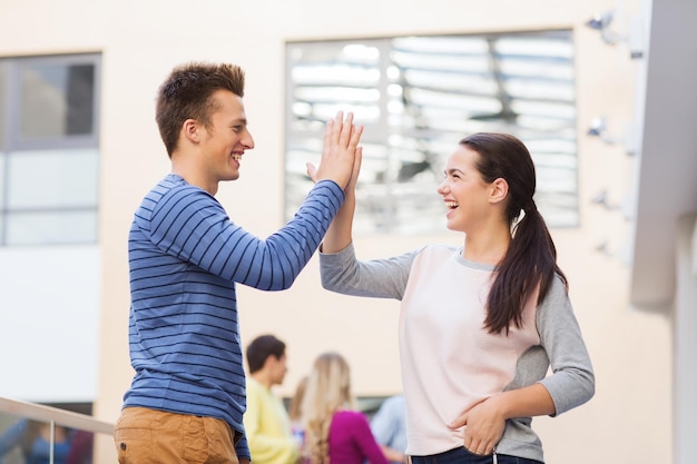 friendship, gesture, education and people concept - group of smiling students outdoors making high five