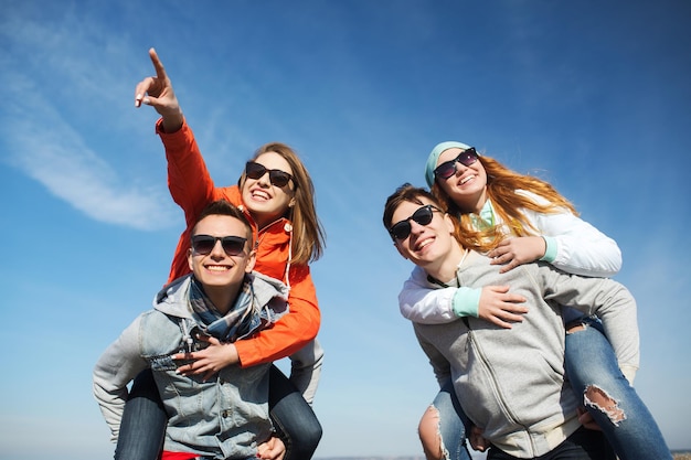 Concetto di amicizia, tempo libero e persone - gruppo di amici adolescenti felici in occhiali da sole che si divertono all'aperto