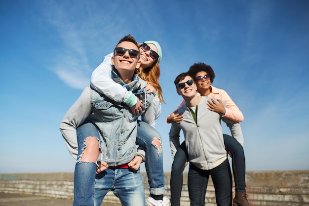 friendship, leisure and people concept - group of happy teenage friends in sunglasses having fun outdoors