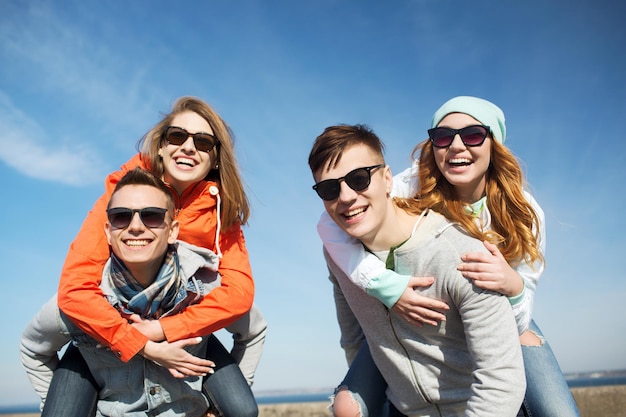 friendship, leisure and people concept - group of happy teenage friends in sunglasses having fun outdoors