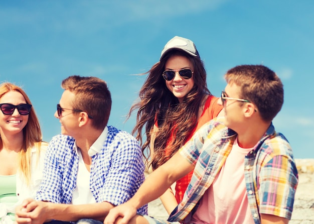 friendship, leisure, summer and people concept - group of smiling friends sitting on city street