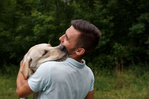 人と犬の友情。幸せな若い男が彼の友人と遊んでいます。