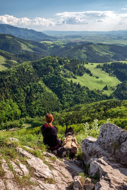 Photo friendship between man and dog young girl siitting on top of the hill with her dog bandog