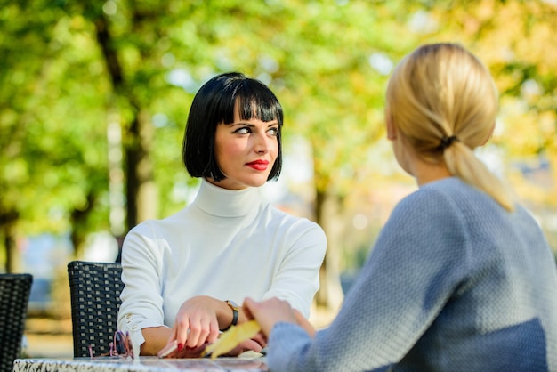 Friendship meeting friendship or rivalry girls friends drink\
coffee talk conversation of two women cafe terrace friendship\
friendly close relations revelation and support trustful\
communication