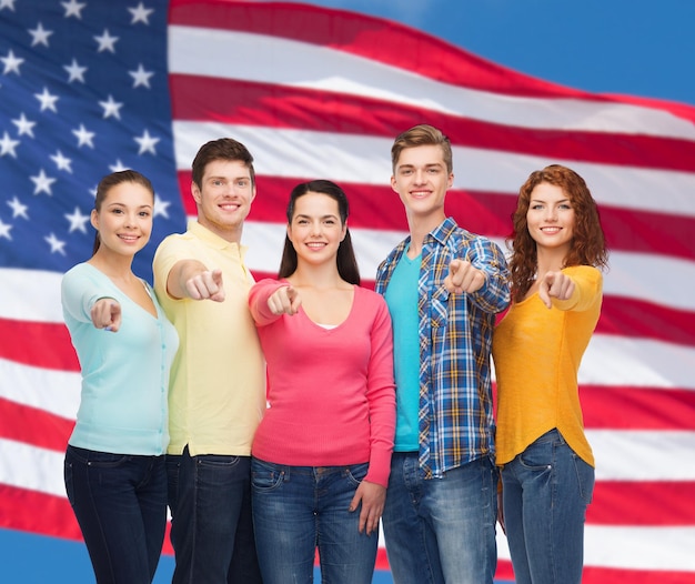 friendship, patriotism and people concept - group of smiling teenagers standing over american flag background