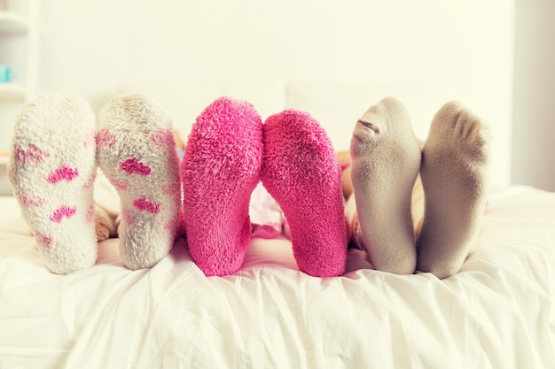 友情,人々,そしてパジャマパーティーコンセプト - 家でベッドで靴下を履いた女性のクローズアップ