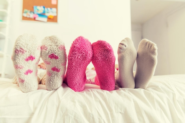 友情、人、パジャマ パーティー コンセプト - 自宅のベッドで靴下を履いた女性の足のクローズ アップ