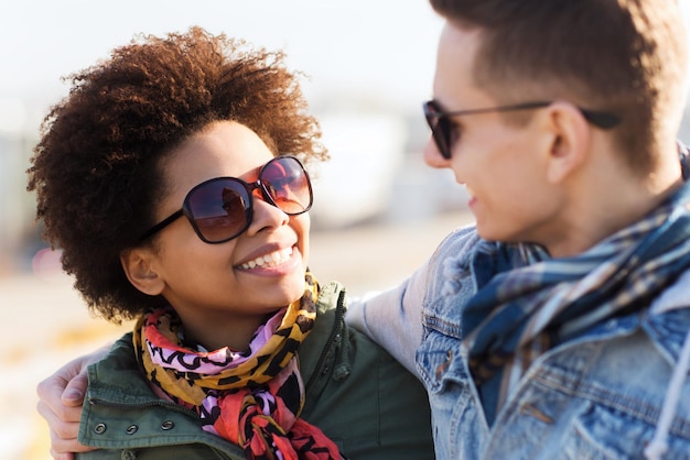 friendship, relations, tourism, travel and people concept - group of happy teenage friends or couple in sunglasses talking outdoors