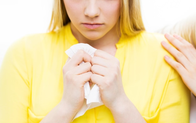 friendship, support, heartbreak and people concept - close up of crying teenage girl comforted by friend