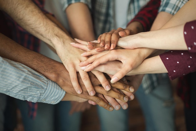 Friendship and teamwork. Multiethnic company of friends stacked hands together, copy space