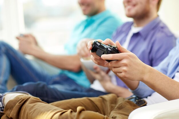 写真 友情、技術、ゲーム、家庭のコンセプト – 家でビデオゲームをしている男性の友人の接写