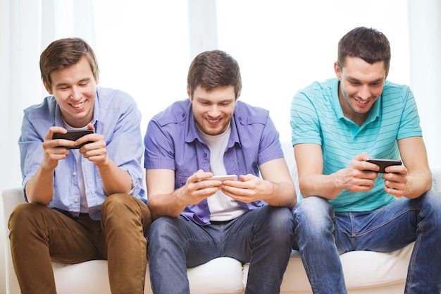 friendship, technology and home concept - smiling male friends with smartphones at home