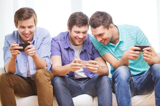 friendship, technology and home concept - smiling male friends with smartphones at home