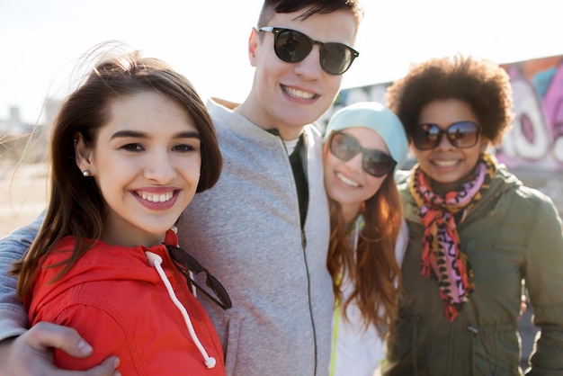 friendship, tourism, travel and people concept - group of happy teenage friends in sunglasses hugging outdoors