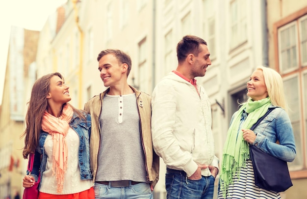 friendship, travel and vacation concept - group of smiling friends walking in the city