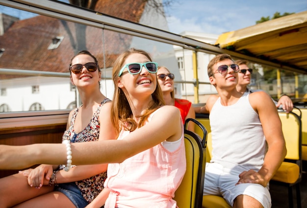 Concetto di amicizia, viaggi, vacanze, estate e persone - gruppo di amici sorridenti che viaggiano in autobus turistico